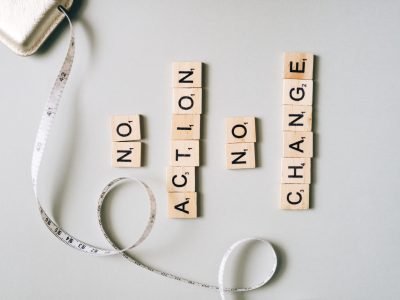 Scrabble tiles form motivational message ‘No Action No Change’ with a measuring tape.